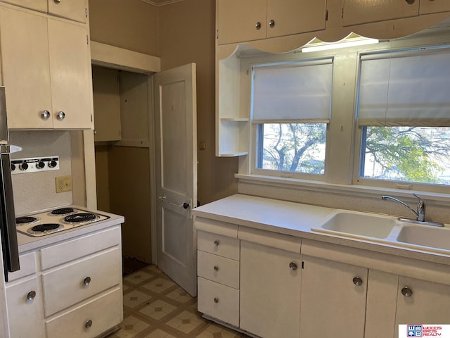 kitchen featuring tasteful backsplash, white electric stovetop, sink, and white cabinets