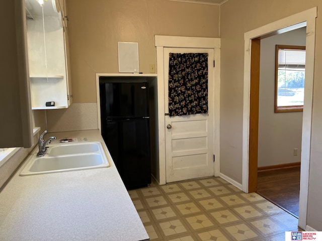 kitchen featuring white cabinets, black fridge, and sink