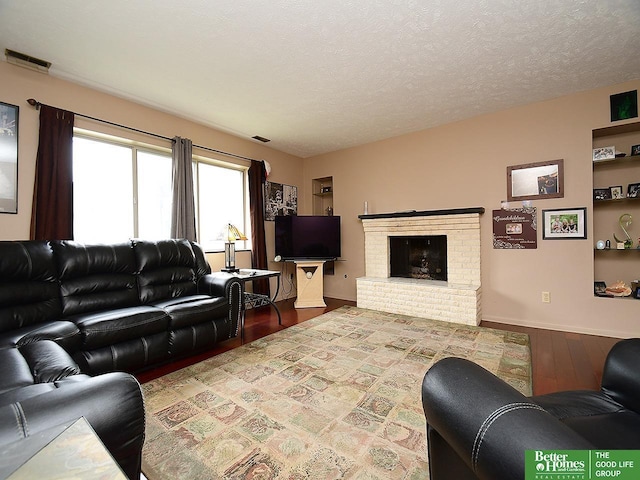 living room featuring hardwood / wood-style flooring, a fireplace, and a textured ceiling