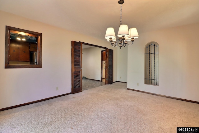 spare room featuring carpet floors and an inviting chandelier