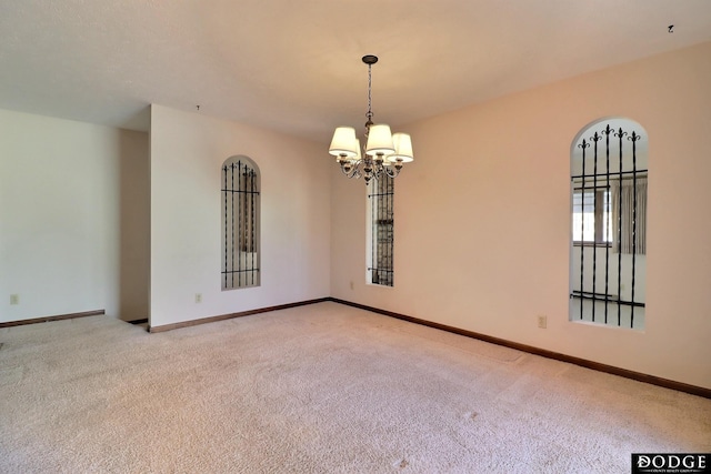 unfurnished room with light colored carpet and an inviting chandelier