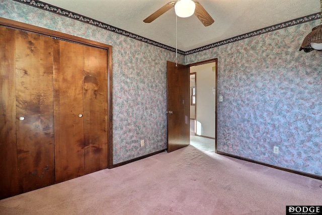 unfurnished bedroom featuring a textured ceiling, a closet, ceiling fan, and light colored carpet