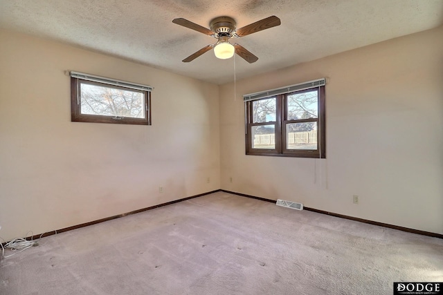 carpeted spare room featuring ceiling fan and a textured ceiling