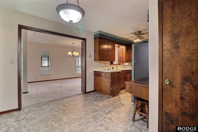 kitchen featuring ceiling fan with notable chandelier and light carpet