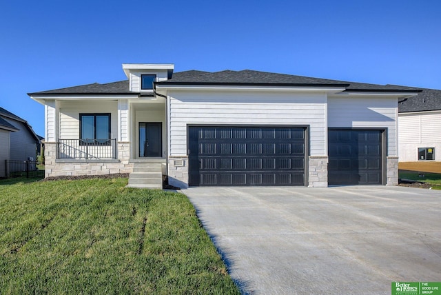 prairie-style house featuring a porch, a front yard, and a garage