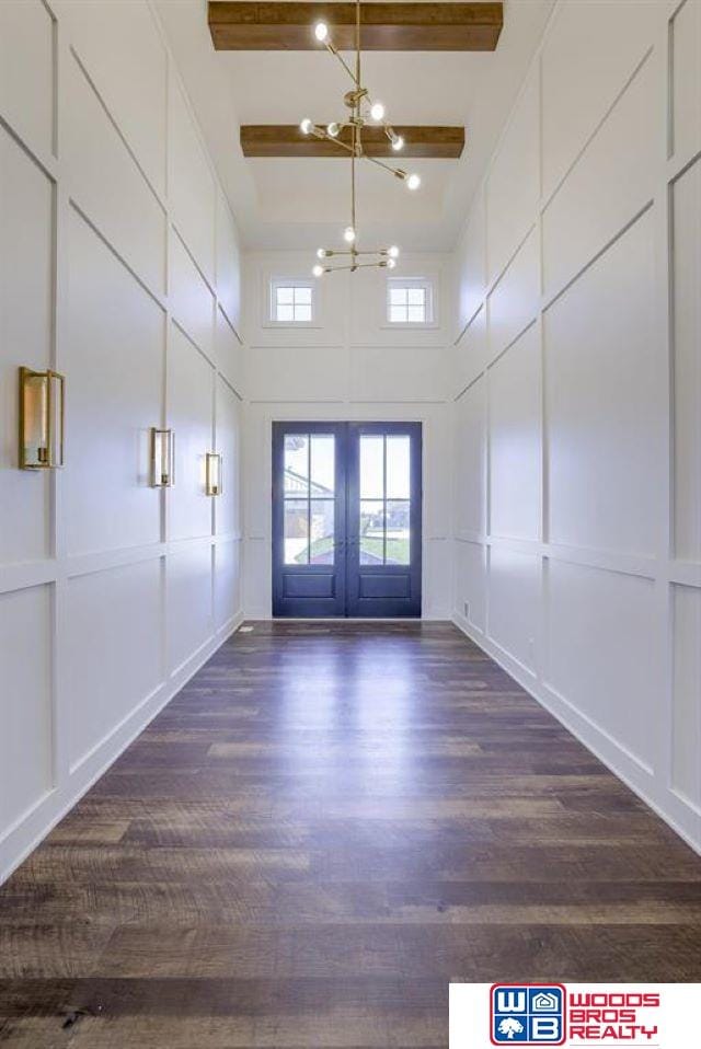 unfurnished room with a notable chandelier, dark hardwood / wood-style flooring, a towering ceiling, and french doors