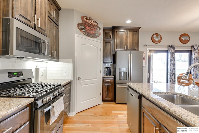 kitchen with light stone countertops, appliances with stainless steel finishes, backsplash, and sink