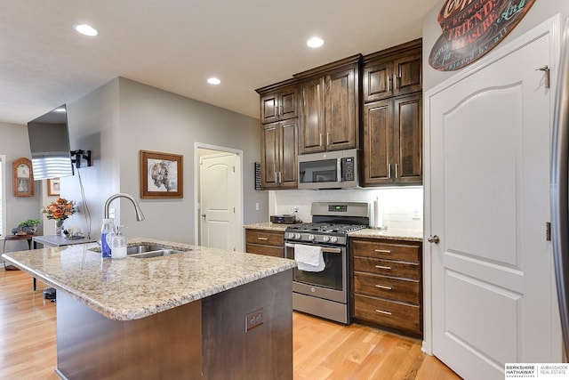 kitchen featuring sink, an island with sink, dark brown cabinets, and appliances with stainless steel finishes