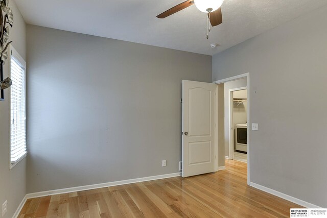 unfurnished room featuring washer / clothes dryer, ceiling fan, light hardwood / wood-style flooring, and plenty of natural light