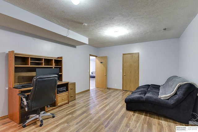 home office with wood-type flooring and a textured ceiling