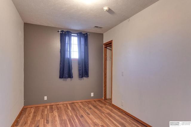 spare room featuring wood-type flooring and a textured ceiling