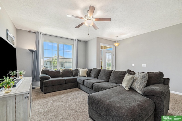 living room with ceiling fan, a healthy amount of sunlight, light colored carpet, and a textured ceiling