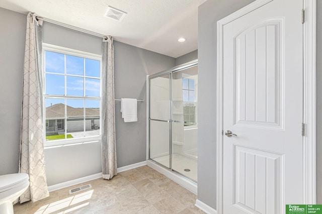 bathroom featuring a textured ceiling, an enclosed shower, and toilet