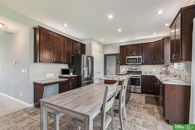 kitchen featuring light stone countertops, sink, a center island, and stainless steel appliances