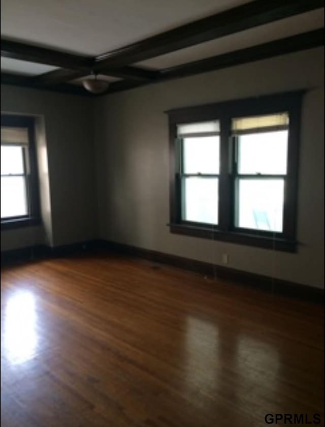 spare room featuring beamed ceiling, dark hardwood / wood-style floors, a healthy amount of sunlight, and coffered ceiling