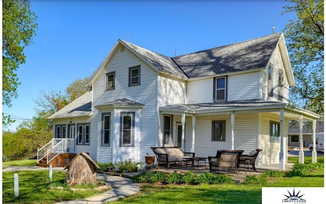 back of house with an outdoor living space, a yard, and a patio