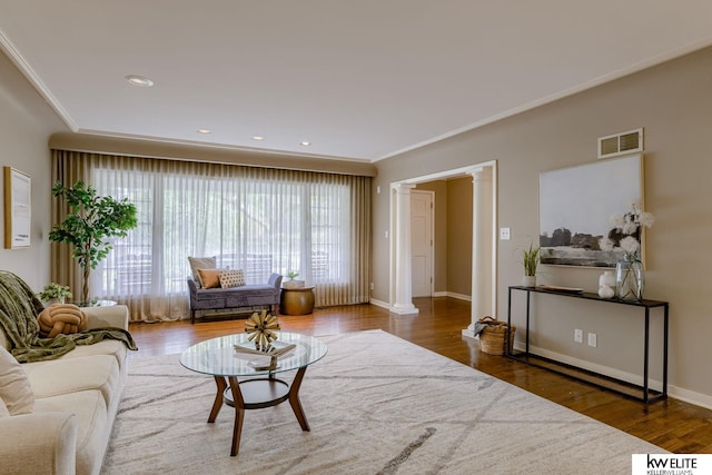 living room featuring dark hardwood / wood-style floors, ornate columns, and crown molding