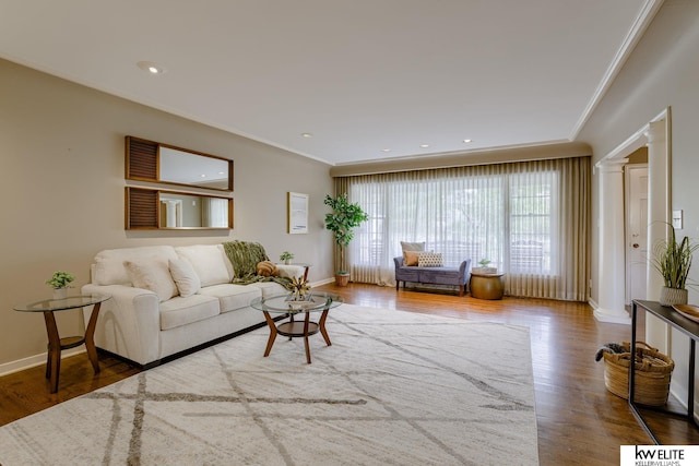 living room featuring decorative columns, hardwood / wood-style flooring, and crown molding