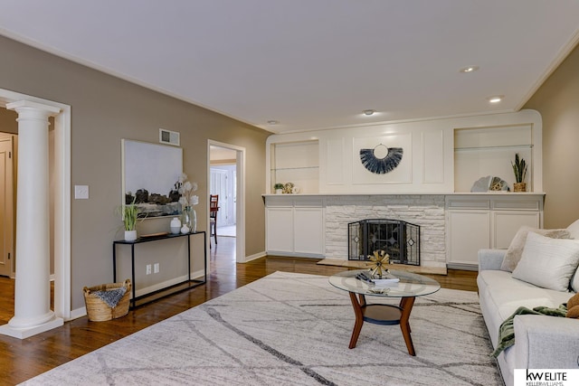 living room featuring a fireplace, dark hardwood / wood-style floors, and ornate columns