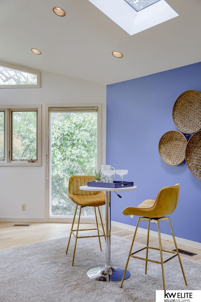 dining area featuring light hardwood / wood-style flooring and vaulted ceiling with skylight