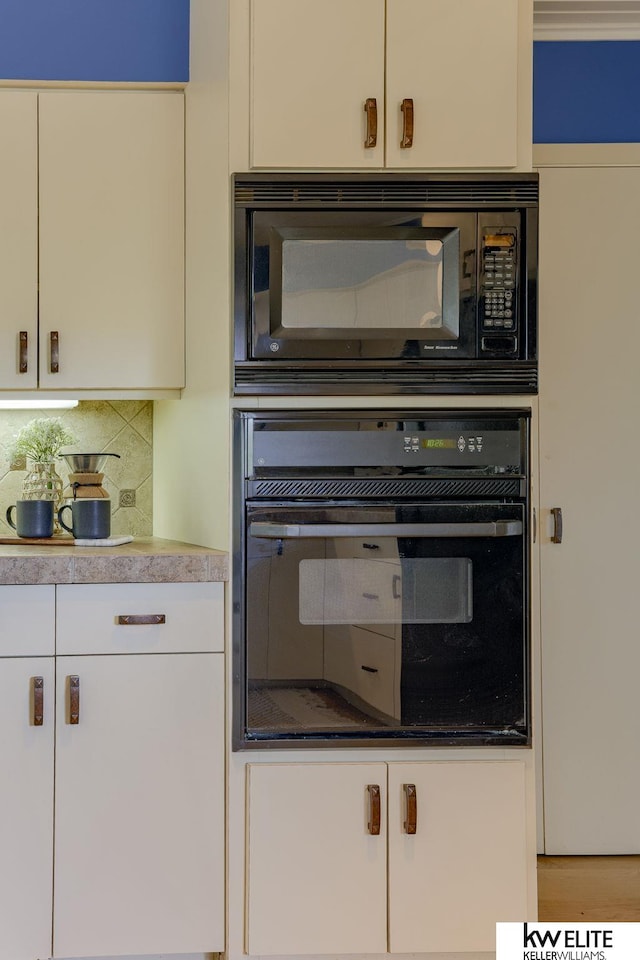 kitchen with white cabinets, backsplash, and black appliances