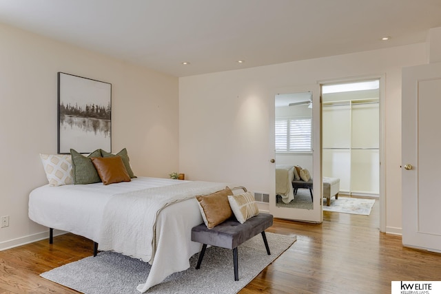 bedroom with a closet, a walk in closet, and light hardwood / wood-style flooring