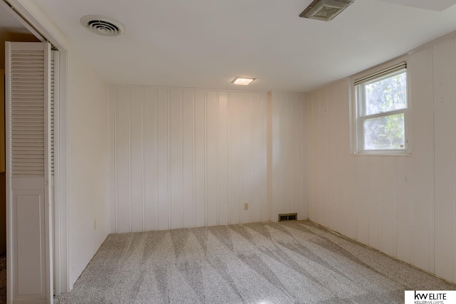 empty room with carpet flooring and wooden walls