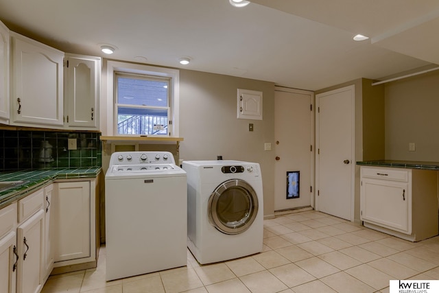 laundry area with washer and dryer, cabinets, and light tile patterned floors