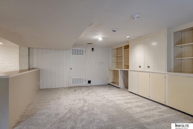 carpeted empty room featuring built in features and wooden walls