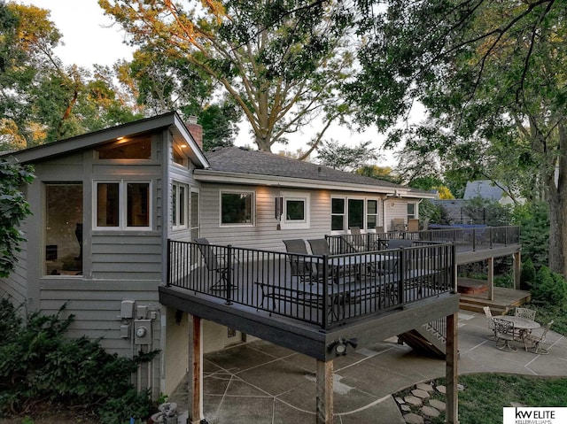 back of house with a wooden deck and a patio