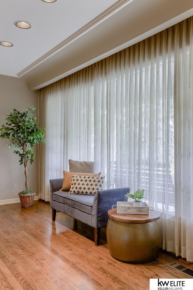 living area featuring hardwood / wood-style flooring and ornamental molding