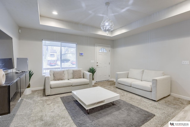 living room with a raised ceiling and a notable chandelier