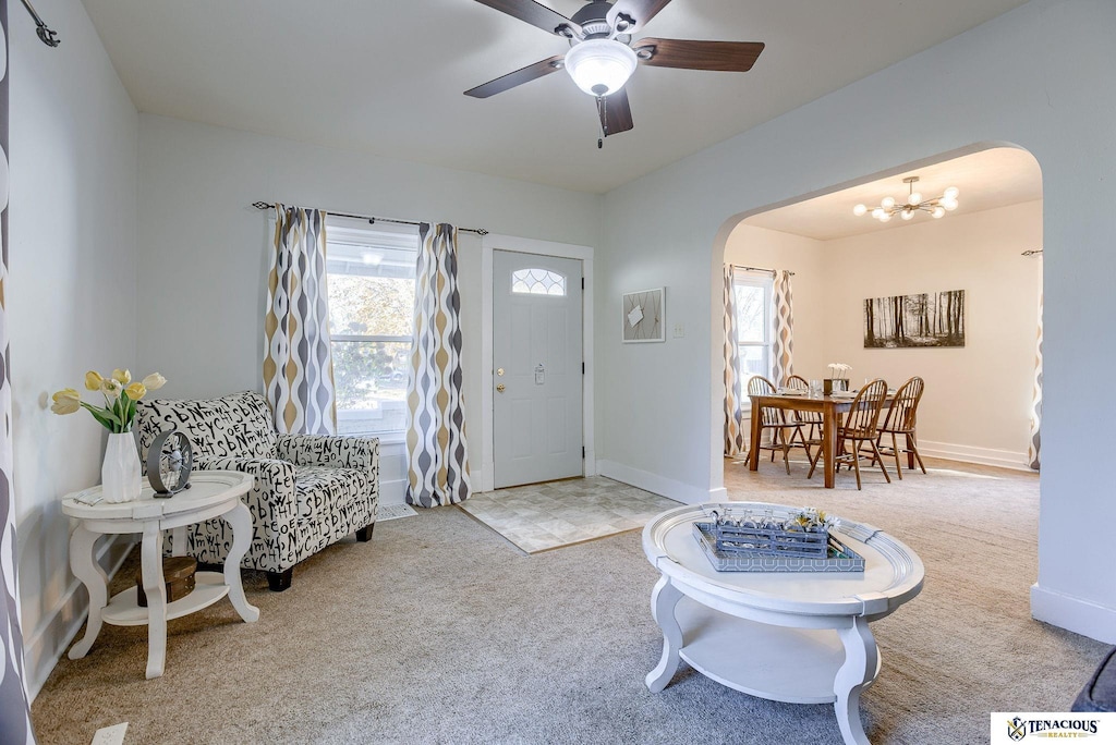 carpeted entrance foyer with ceiling fan with notable chandelier