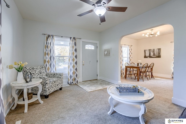 carpeted entrance foyer with ceiling fan with notable chandelier