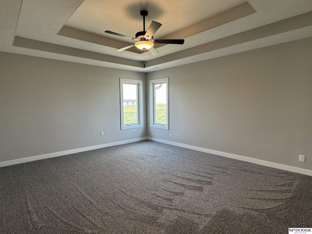 carpeted spare room with a tray ceiling and ceiling fan