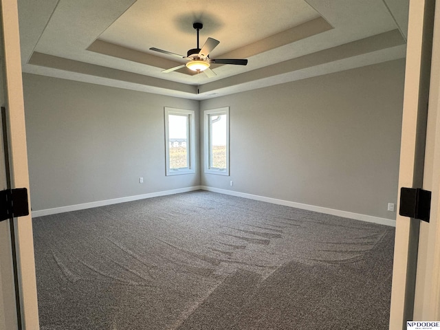 carpeted spare room featuring a tray ceiling and ceiling fan