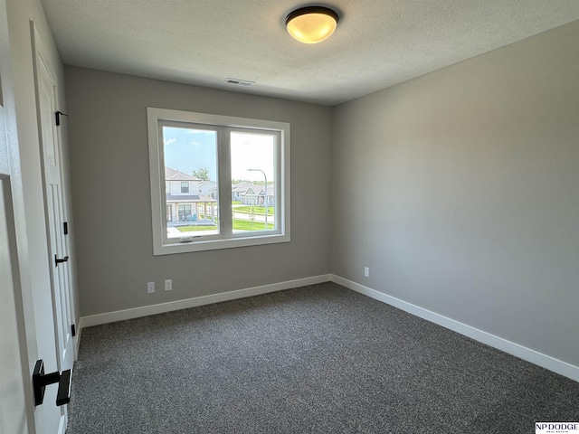 empty room with dark carpet and a textured ceiling