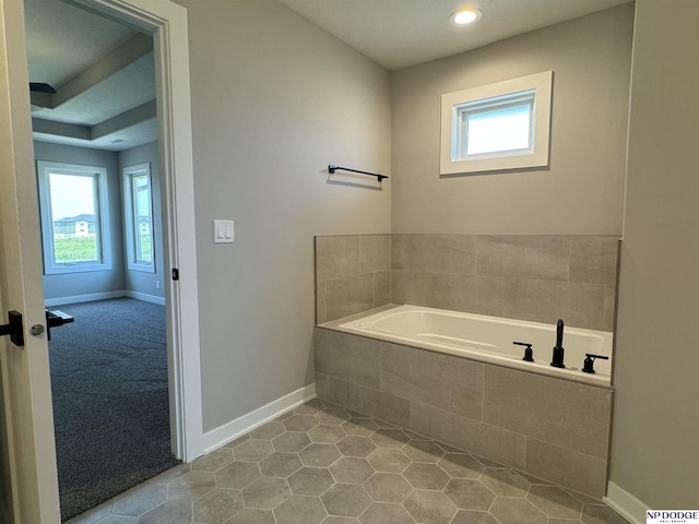 bathroom with tile patterned flooring and tiled tub