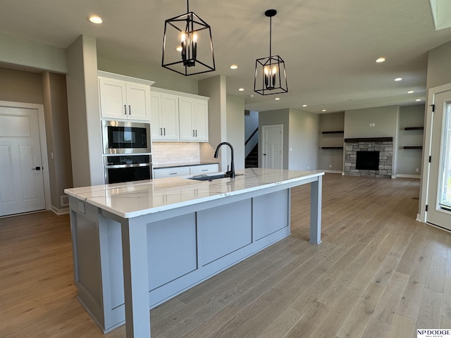 kitchen featuring pendant lighting, sink, a fireplace, white cabinetry, and stainless steel appliances