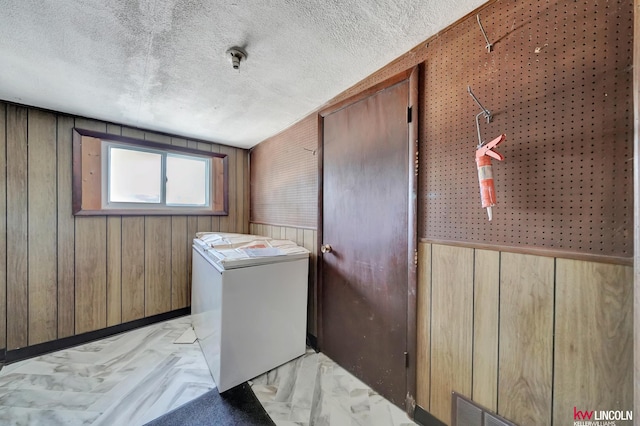 laundry area featuring wooden walls and a textured ceiling