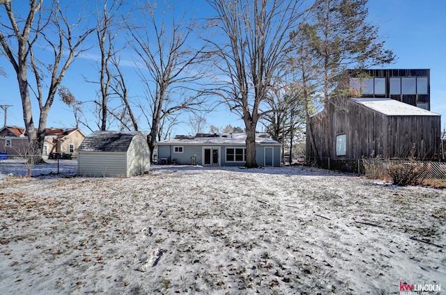 snow covered back of property with an outbuilding