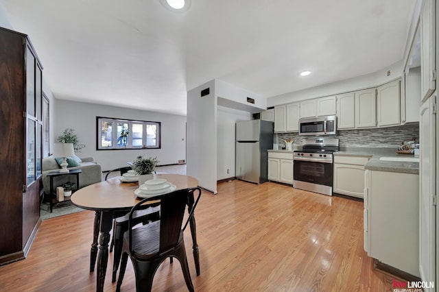 kitchen featuring backsplash, light hardwood / wood-style flooring, white cabinets, and appliances with stainless steel finishes