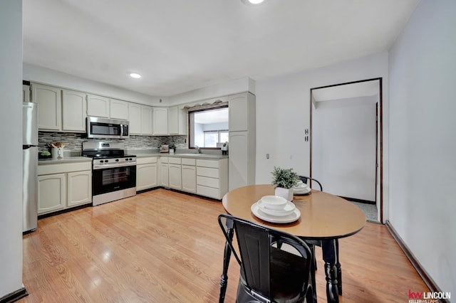 kitchen featuring white cabinetry, light wood-type flooring, stainless steel appliances, and tasteful backsplash