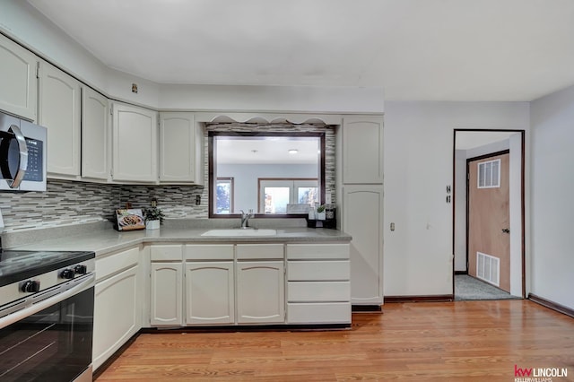 kitchen with white cabinets, light hardwood / wood-style floors, sink, and appliances with stainless steel finishes