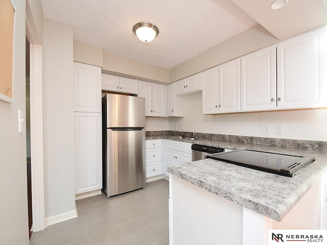 kitchen with a textured ceiling, kitchen peninsula, white cabinetry, and stainless steel appliances