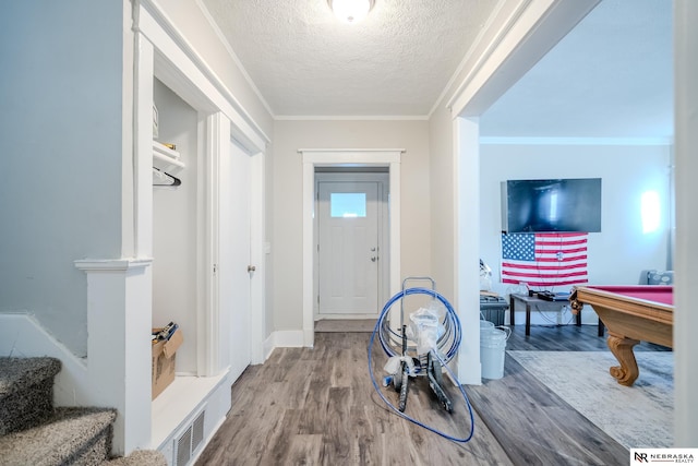 foyer featuring wood-type flooring, a textured ceiling, ornamental molding, and billiards