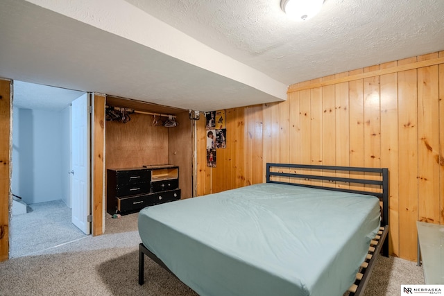 bedroom with a textured ceiling, light colored carpet, and wooden walls