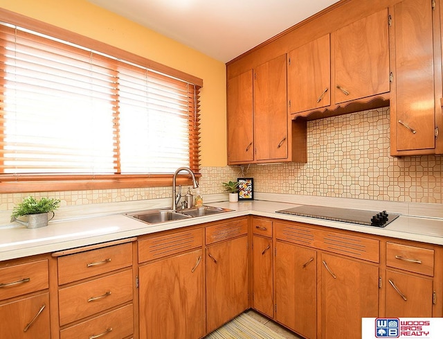 kitchen featuring backsplash, cooktop, and sink