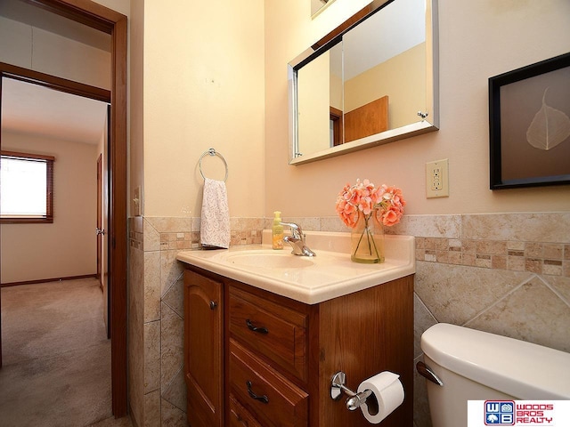 bathroom with vanity, toilet, and tile walls