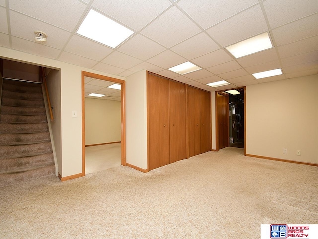 basement featuring a paneled ceiling and light colored carpet